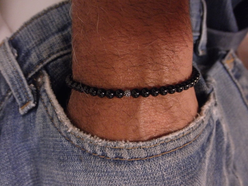 Puede incluir: Un brazalete de cuentas negras con un acento de cuentas plateadas.