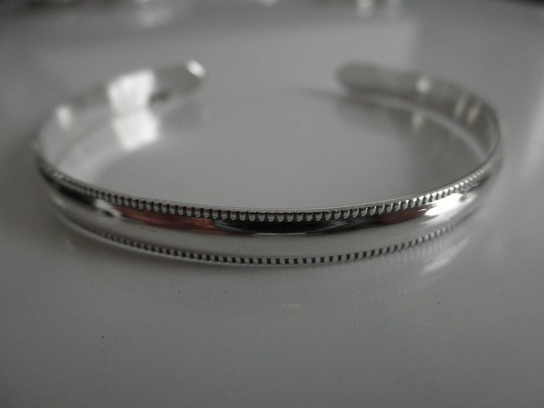 May include: A silver bangle bracelet with a beaded edge.