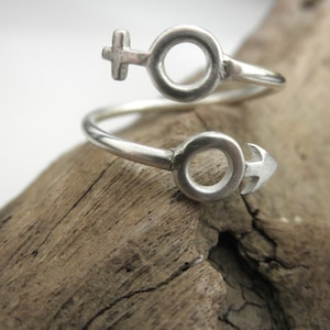 May include: A silver ring with a twisted design featuring the male and female symbols.