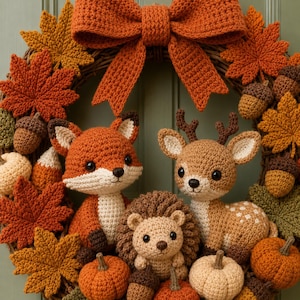 May include: A decorative wreath featuring a large orange crocheted bow at the top, adorned with crocheted autumn leaves, acorns, and pumpkins. Centered are three crocheted figures: a fox, a hedgehog, and a deer with small brown antlers.