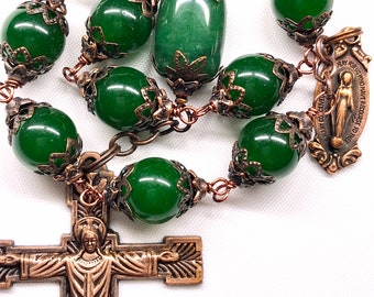 Könnte beinhalten: Eine grüne Jade-Rosenkranz mit einem bronzenen Kruzifix und einer bronzenen Medaille mit der Jungfrau Maria. Die Rosenkranzperlen sind auf einem Kupferdraht aufgefädelt.