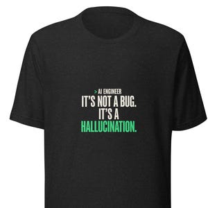 May include: A charcoal grey short-sleeved t-shirt featuring the white and green text: > AI ENGINEER IT'S NOT A BUG. IT'S A HALLUCINATION. The shirt has a crew neckline and a standard fit, with the graphic centred on the chest area of the garment.