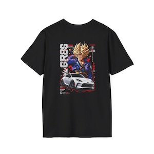 Puede incluir: Una camiseta negra de manga corta con un estampado gráfico de un personaje de anime rubio con una espada detrás de un coche deportivo Toyota GR86 blanco. El diseño incluye el texto GR86, Toyota y caracteres japoneses en rojo y blanco.
