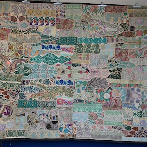 Peut inclure: Une grande tenture murale ou courtepointe rectangulaire présentant un motif en patchwork composé de nombreux segments de tissu. Le textile affiche une variété de motifs complexes, incluant des fleurs, des formes cachemire et des bordures.