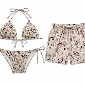 Pode incluir: Um conjunto de biquíni composto por um top triangular com alças de pescoço e cueca com laços laterais, combinado com calções de banho a condizer com cintura elástica e cordão, tudo decorado com um padrão floral paisley preto e pêssego.