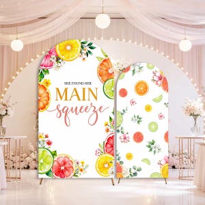 May include: Two arched backdrop covers featuring a white background with watercolor illustrations of oranges, grapefruits, and limes, along with small white flowers and green leaves. The larger arch displays the text SHE FOUND HER MAIN squeeze.