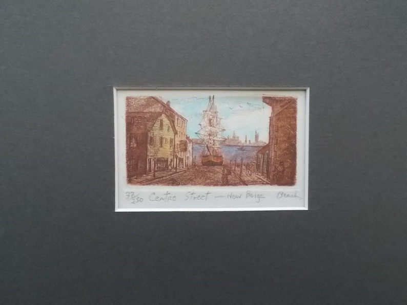 以下が含まれることがあります： 港の風景を描いた芸術的なプリント。高い帆船と水辺に並ぶ建物が特徴です。アートワークは茶色の色調で、青い空と水があります。「33/50 Centre Street - New Burga Beach」の文字が見えます。