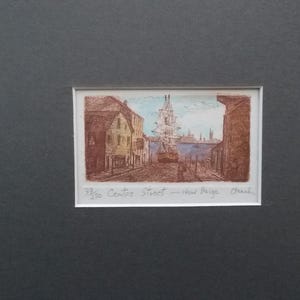 以下が含まれることがあります： 建物と帆船のある港の風景の額入りプリント。アートワークは茶色の色合いで、青い空と水があります。「33/50 Centre Street - New Paige Beach」というテキストが下にあります。