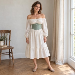 May include: An off-the-shoulder cream-colored midi dress with long, billowy sleeves and a tiered skirt, featuring a sage green corset-style waist cincher with a vertical row of four white buttons down the center front.