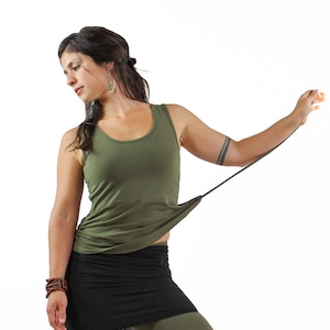 May include: A woman wearing a green tank top with a black skirt and green leggings. The tank top has a tie at the bottom and the skirt is a wrap style.