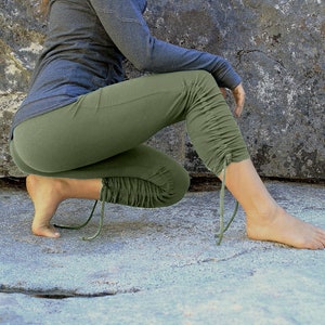 May include: A pair of olive green yoga pants with a drawstring at the ankle. The pants are made of a soft, stretchy fabric and are perfect for yoga, Pilates, or other workouts.