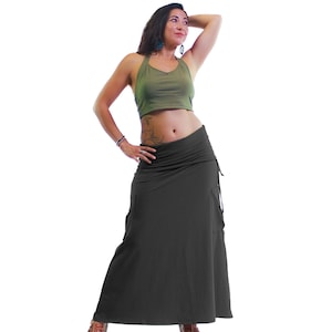 May include: A woman wearing a green crop top and a long, dark gray skirt. The skirt has a gathered waist and a flowing silhouette.