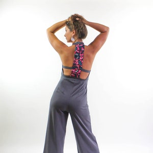 May include: A gray jumpsuit with a floral patterned back detail. The jumpsuit has a wide leg and a tie at the ankle.