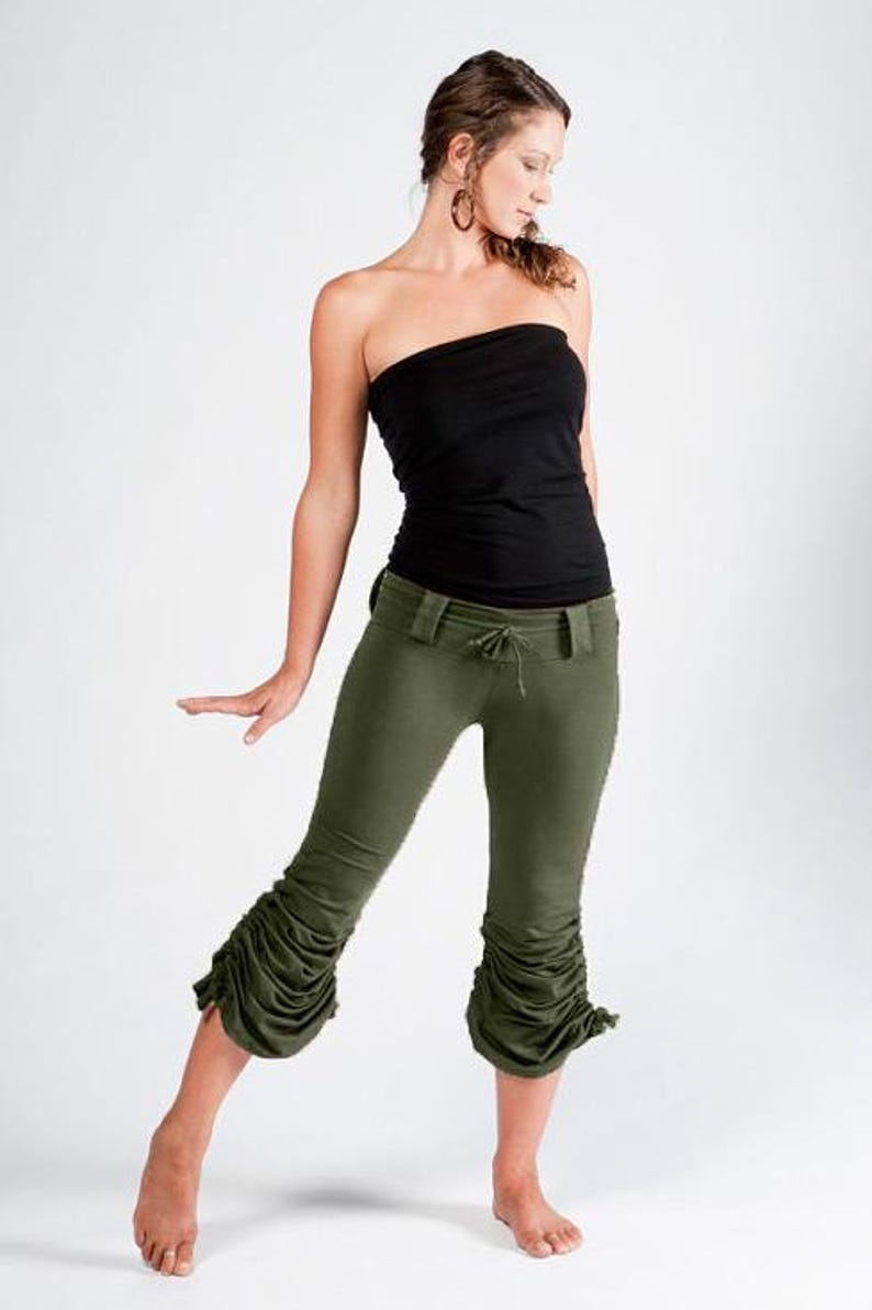 May include: A woman wearing a black strapless top and olive green pants with a gathered detail at the bottom. The pants have a drawstring waist.