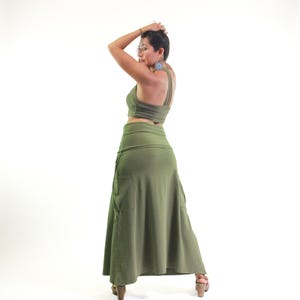 May include: A woman wearing a green crop top and a long, flowing green skirt with a pocket. The skirt is gathered at the waist and has a flowing, A-line shape.