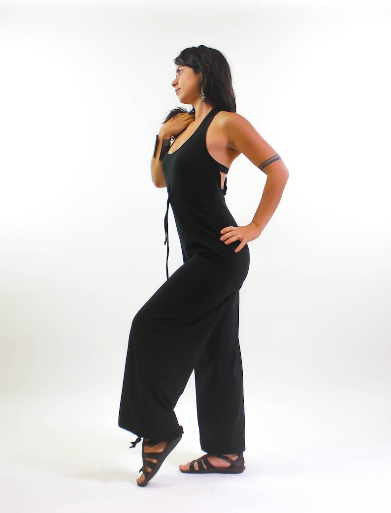 May include: A black sleeveless jumpsuit with a wide leg. The jumpsuit has a scoop neck and a tie at the waist.
