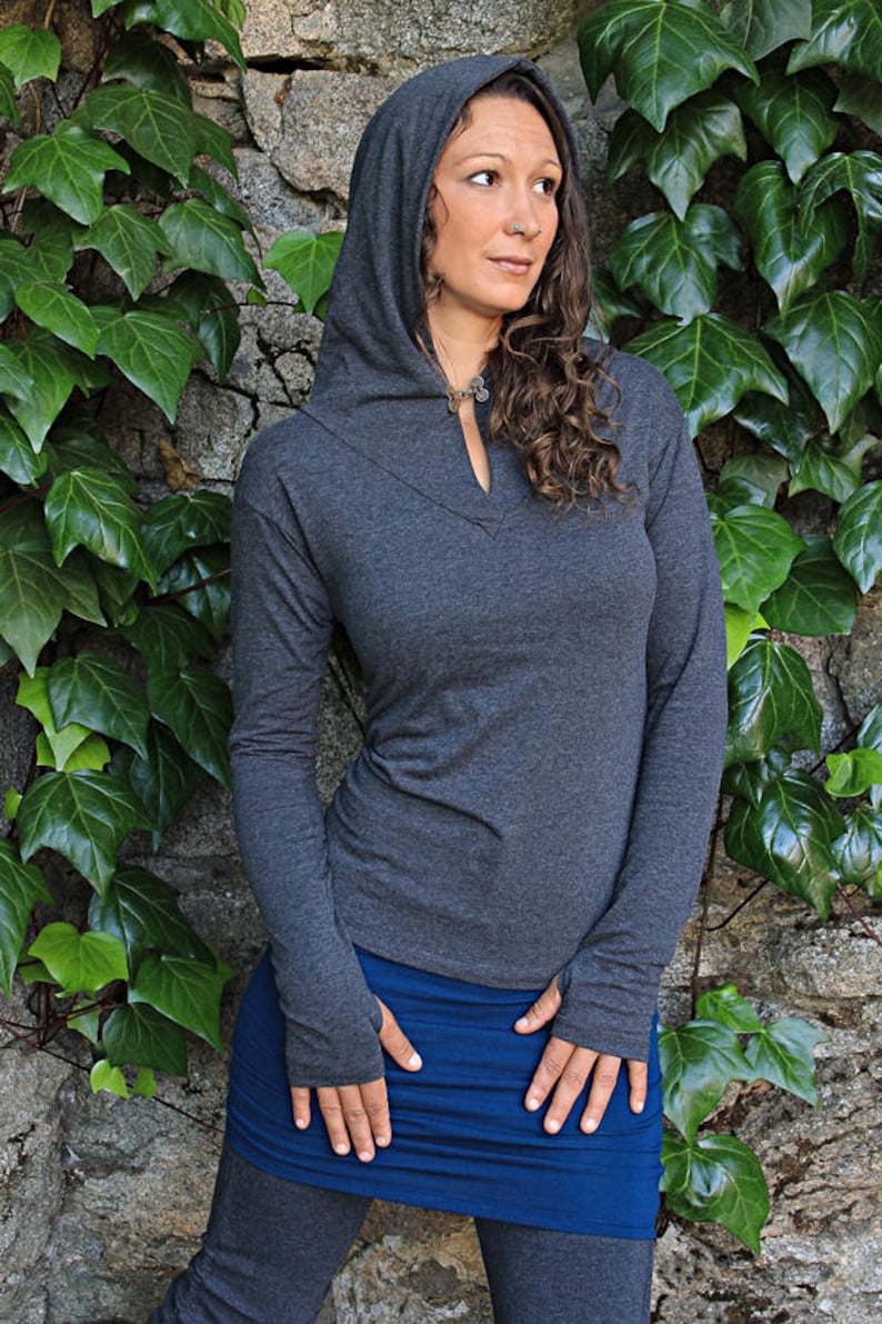 May include: A charcoal gray hooded sweatshirt with a long sleeve and thumb holes. The sweatshirt has a V-neck and a small silver pendant necklace.