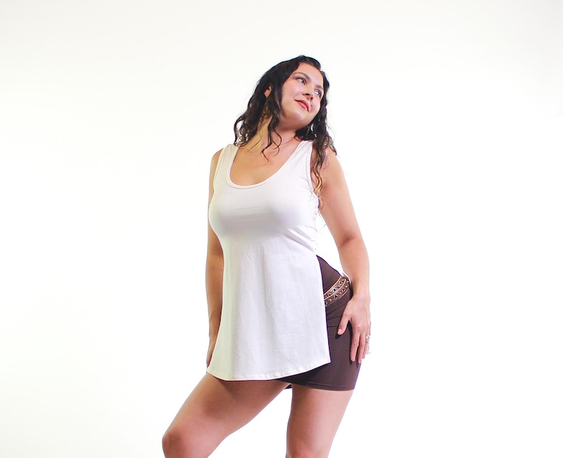May include: A white tank top with a side slit and a brown skirt. The tank top has a scoop neck and a relaxed fit.