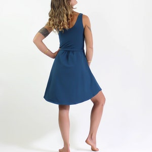 May include: A teal blue sleeveless dress with a fitted bodice and a flowing skirt. The dress has a gathered waistline and a scoop neckline.