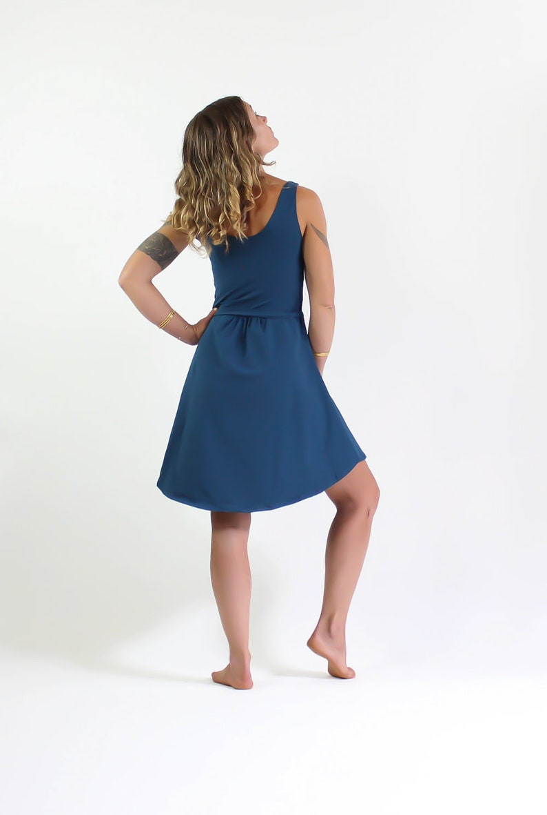 May include: A teal blue sleeveless dress with a fitted bodice and a flowing skirt. The dress has a gathered waistline and a scoop neckline.