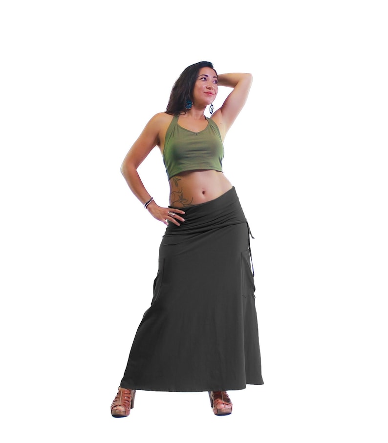 May include: A woman wearing a green crop top and a long, dark gray skirt. The skirt has a gathered waist and a flowing silhouette.