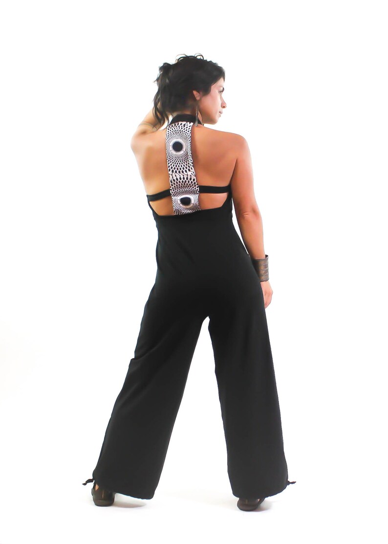 May include: A black jumpsuit with a wide-leg silhouette and a geometric patterned back detail. The jumpsuit has a halter neckline and a low back.