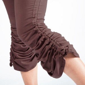 May include: Brown cropped pants with a gathered detail at the bottom of the legs.