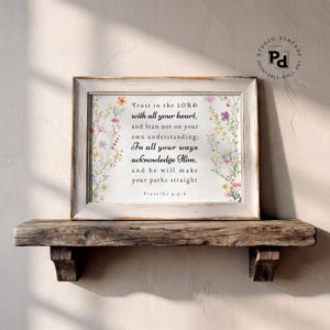 May include: A framed wall art print featuring the Bible verse Proverbs 3:5-6 in black serif text, surrounded by a delicate watercolour border of colourful wildflowers on both sides, encased in a light-toned, weathered wooden frame.