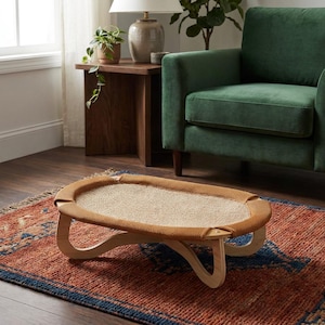 May include: An oval pet bed featuring a light-coloured woven mesh centre panel surrounded by a textured mustard-yellow fabric border, supported by a curved light-toned wooden frame with four distinct legs resting on a patterned rug.