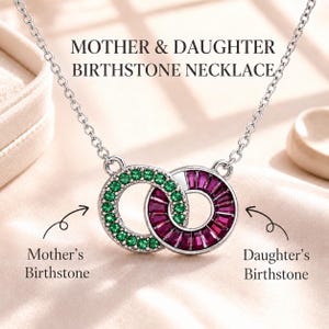 May include: A silver necklace featuring two interlocking circular pendants. One circle is set with round green stones, and the other is set with baguette-cut magenta stones. Text reads: MOTHER & DAUGHTER BIRTHSTONE NECKLACE, Mother's Birthstone, Daughter's Birthstone.