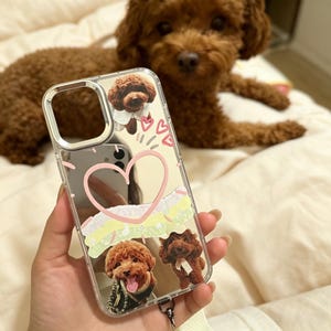 May include: A clear phone case featuring a custom design with three photographic images of a brown poodle, a large pink heart outline, smaller pink heart accents, and horizontal pastel-colored brushstroke graphics printed on the surface.