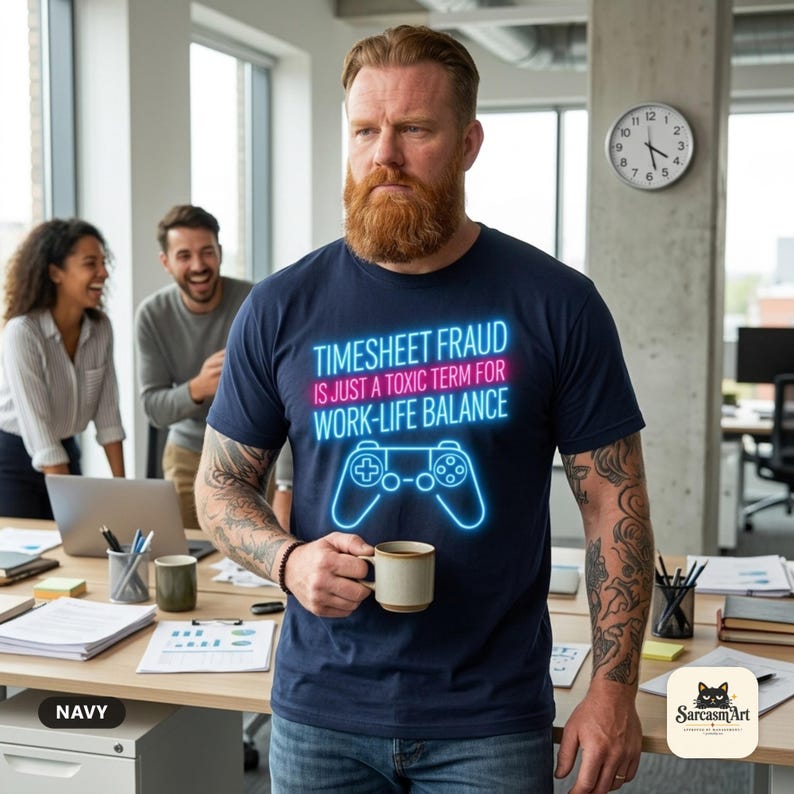Bearded man with a coffee in an office wearing the "Timesheet Fraud Is Just a Toxic Term for Work-Life Balance" neon gamer T-shirt by SarcasmArt in Navy – a funny coworker gift for gamers.