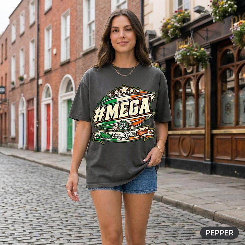 Woman on a cobblestone street in Dublin wearing the "#MEGA Make Europe Great Again" Ireland T-shirt by SarcasmArt in Pepper – a satirical #MEGA collection shirt with a retro #MEGA sports badge with the green-white-orange Irish tricolour, a Celtic trinity knot, stars and a Make Europe Great Again script banner.