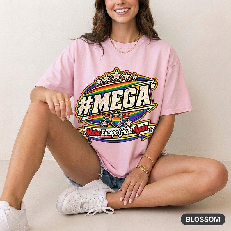 Woman sitting on a stool in a bright studio wearing the "#MEGA Make Europe Great Again" Rainbow Pride T-shirt by SarcasmArt in Blossom.