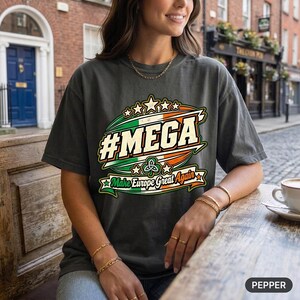 Woman holding a coffee at a café terrace wearing the "#MEGA Make Europe Great Again" Ireland T-shirt by SarcasmArt in Pepper.