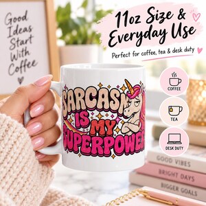 11 oz size and everyday use: a hand holding the "Sarcasm Is My Superpower" unicorn coffee mug by SarcasmArt – perfect for coffee, tea and hot chocolate.