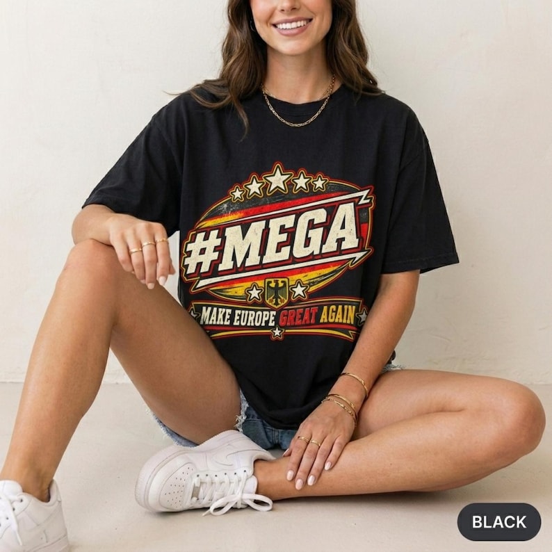 Woman sitting cross-legged in a bright studio wearing the "#MEGA Make Europe Great Again" Germany T-shirt by SarcasmArt in Black.
