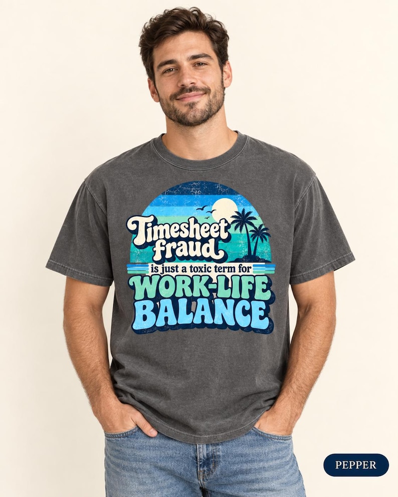 Smiling man wearing the "Timesheet Fraud Is Just a Toxic Term for Work-Life Balance" sarcastic work T-shirt by SarcasmArt in Pepper (washed charcoal), showing the retro sunset work-life balance print.
