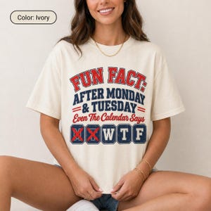 May include: An ivory short-sleeve t-shirt featuring red and navy blue text that reads: FUN FACT: AFTER MONDAY & TUESDAY Even The Calendar Says W T F. The letters W, T, and F are enclosed in navy blue boxes, while the letters M and T are crossed out.