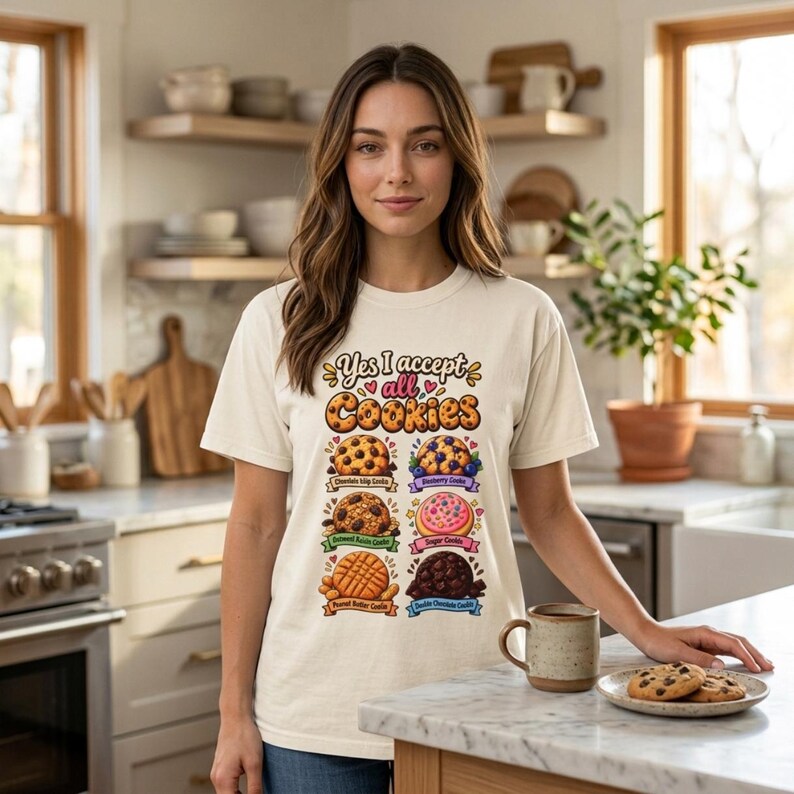 Woman in a cozy kitchen wearing the "Yes, I Accept All Cookies" funny programmer T-shirt by SarcasmArt in Ivory.