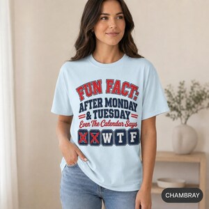 Smiling woman wearing the "Fun Fact: After Monday & Tuesday" WTF varsity work T-shirt by SarcasmArt in Chambray (light blue) – a sarcastic coworker gift.
