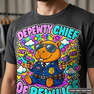Close-up of the "Depewty Chief of Pewlice" capybara meme T-shirt by SarcasmArt in Dark Grey Heather: a capybara police officer in sunglasses and a blue uniform with a badge, surrounded by colorful comic bursts and DEPEWTY CHIEF OF PEWLICE lettering.
