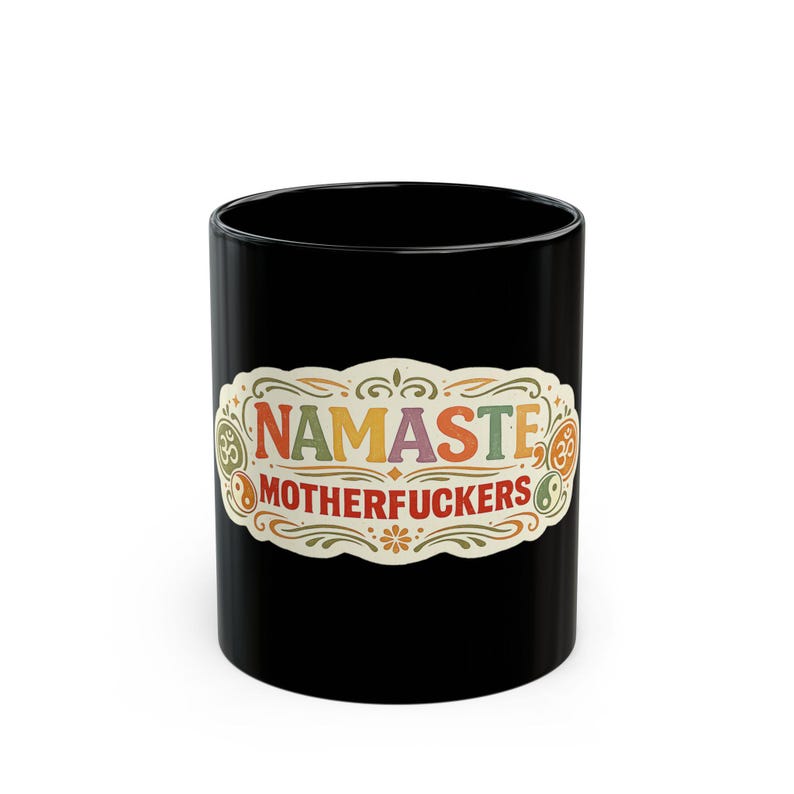 The black "Namaste Motherfuckers" funny yoga coffee mug by SarcasmArt on a white background, showing a colorful boho mandala label with the adult-humor phrase NAMASTE MOTHERFUCKERS in red, orange and teal.