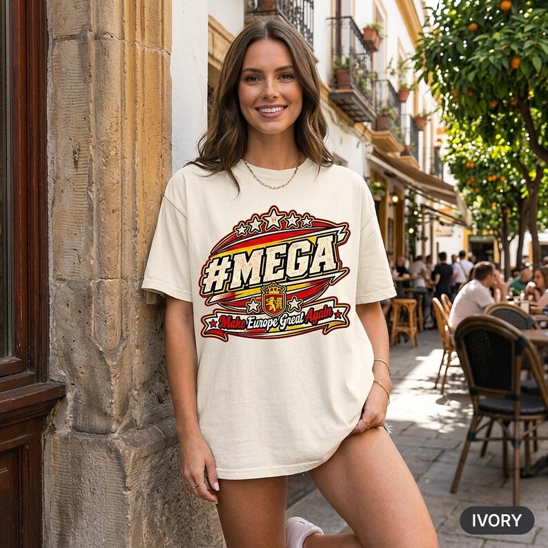 Smiling woman at a European street café wearing the "#MEGA Make Europe Great Again" Spain T-shirt by SarcasmArt in Ivory.