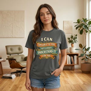 Woman in a mid-century living room wearing the "I Can Explain It to You, But I Can't Understand It for You" sarcastic teacher T-shirt by SarcasmArt in Pepper (washed charcoal).