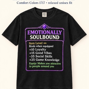 May include: A black t-shirt featuring a purple-bordered graphic resembling a video game item tooltip. The text reads EMOTIONALLY SOULBOUND, Item Level infinity, Binds when equipped, +10 Loyalty, +15 Good Vibes, -35 Social Skills, +25 Game Knowledge, and Equip: Makes you attractive to people around you.