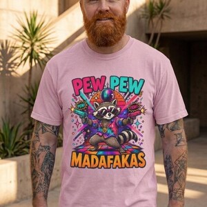 Bearded man wearing the "Pew Pew Madafakas" raccoon meme T-shirt by SarcasmArt in Blossom (soft pink).