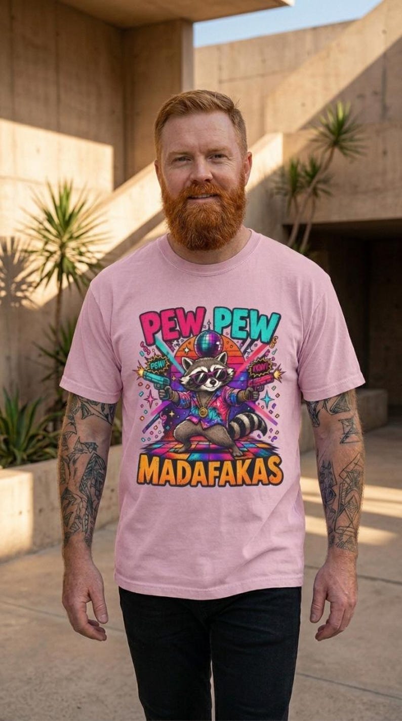 Bearded man wearing the "Pew Pew Madafakas" raccoon meme T-shirt by SarcasmArt in Blossom (soft pink).