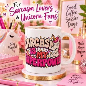 For sarcasm lovers and unicorn fans: the "Sarcasm Is My Superpower" unicorn coffee mug by SarcasmArt on a pink, girly desk with notebooks and pens.