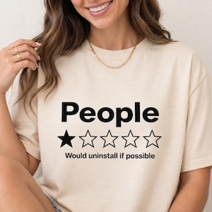 Close-up of the "People – 1 Star, Would Uninstall If Possible" funny review T-shirt by SarcasmArt in Natural worn by a woman – a Bella+Canvas 3001 unisex tee with the word People with a one-out-of-five-star rating and the review Would uninstall if possible in black.
